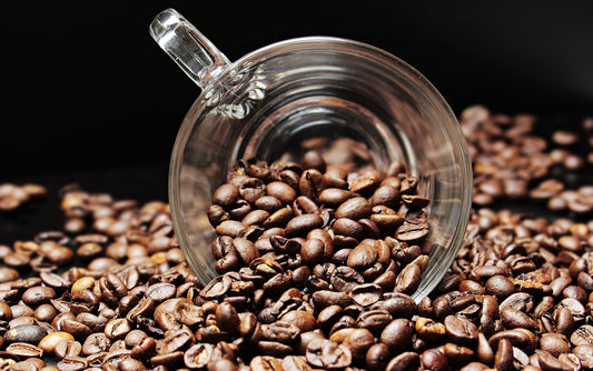 Coffee beans around a glass coffee cup